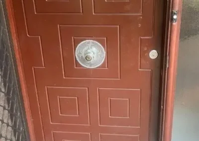 Round silver deadbolt above a lever handle on a white door