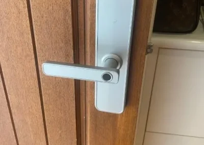 Brass deadbolt on a timber door beside a black gate