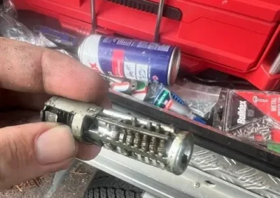 Disassembled lock cylinder held above a red toolbox