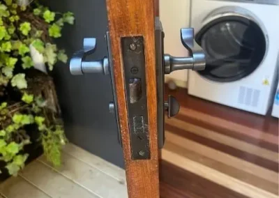 Silver lever handle with round deadbolt on a timber door