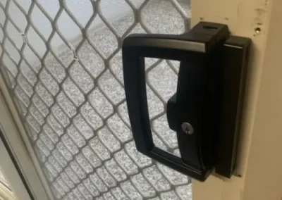Black door handle fitted to a security screen door