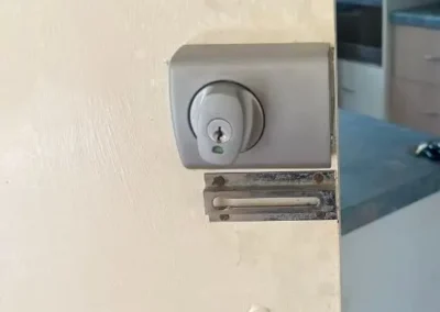 Black round deadbolt above a handle on a white door