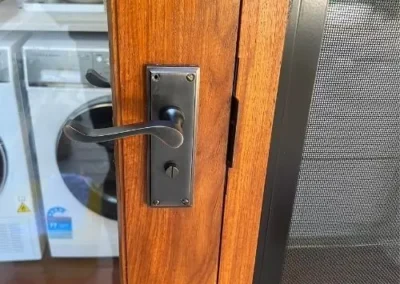 Key inserted into a black round deadbolt on a white door